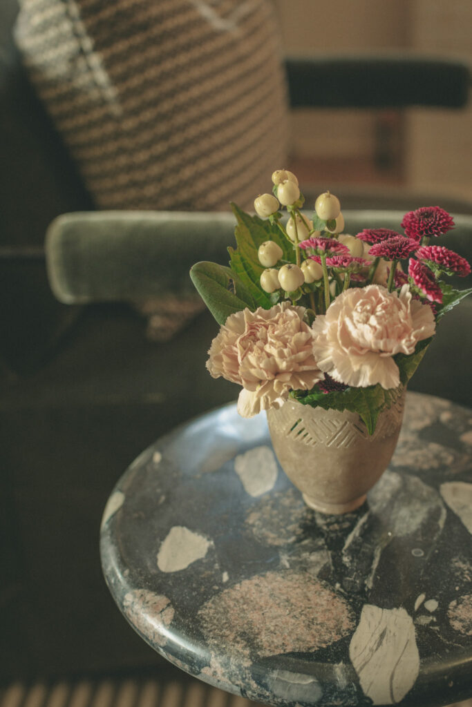 Marble coffee table with fresh flowers in ceramic vase and vintage decorative objects
