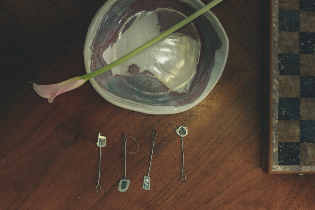 Vintage brass cocktail picks with semi-precious stones on walnut wood surface