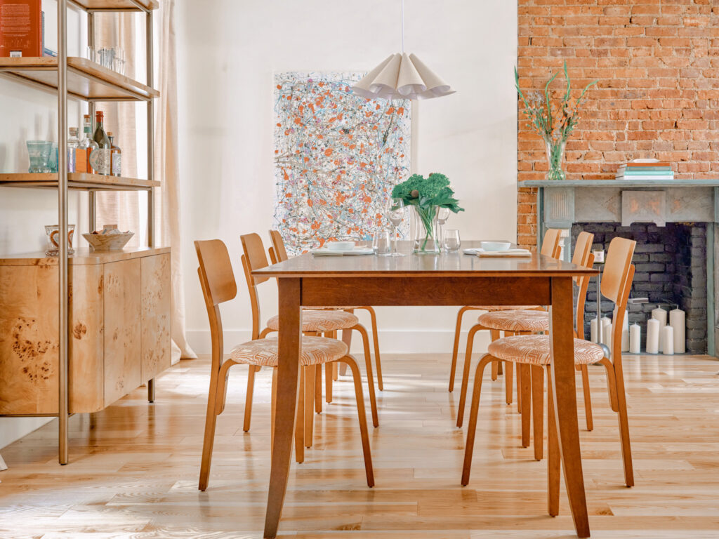 Brooklyn dining room with mid-century modern wood chairs exposed brick fireplace and brass shelving by Tenlie Mourning