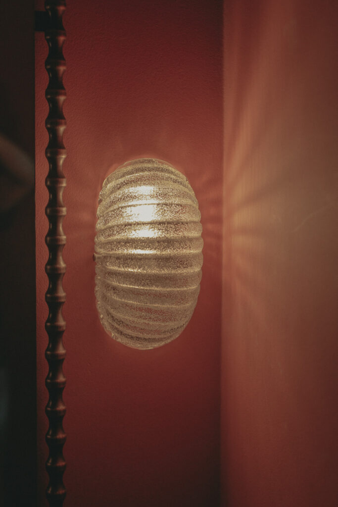 Italian Murano glass sconce with ribbed texture on coral painted wall Madison Street residence. Interior Design by Tenlie Mourning