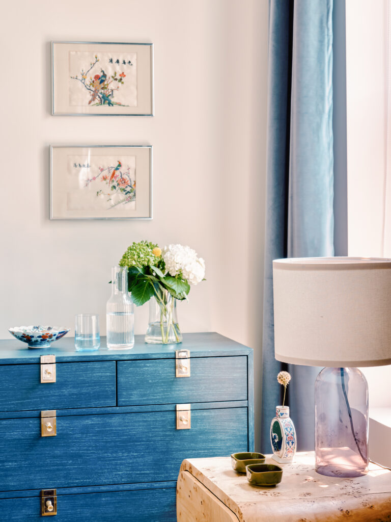 Primary bedroom featuring burl wood nightstand blue velvet dresser and patterned upholstered bed Jefferson Avenue. Interior design by Tenlie Mourning