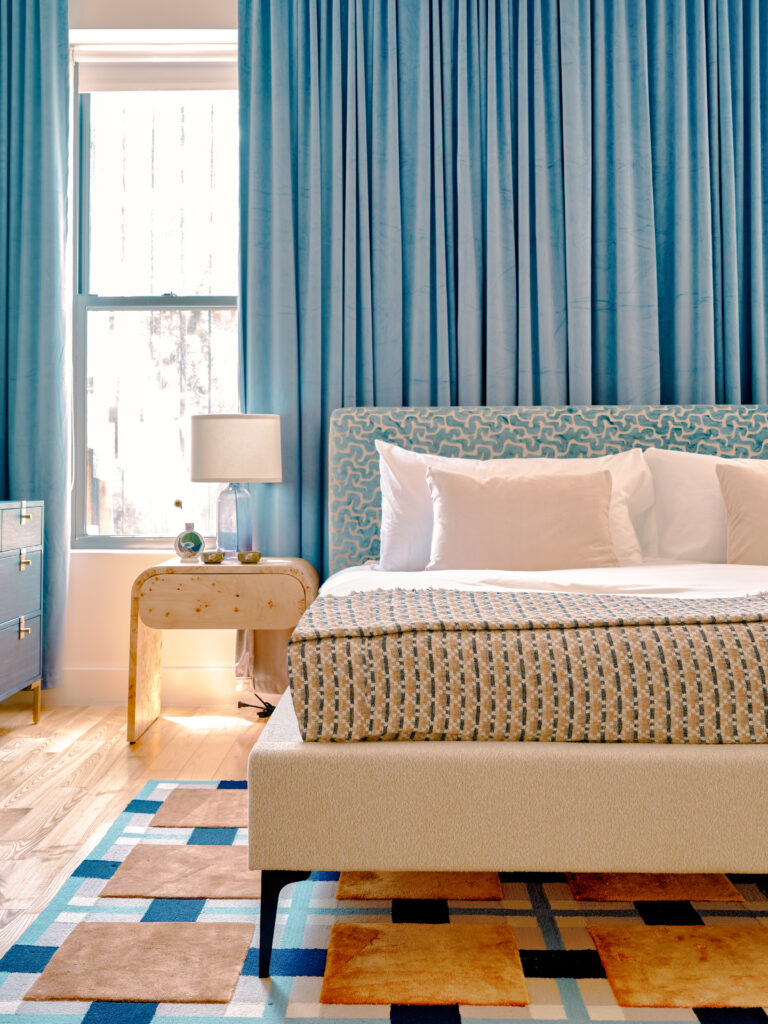 Brooklyn bedroom with custom upholstered headboard teal curtains geometric throw blanket and brass nightstands by Tenlie Mourning. 