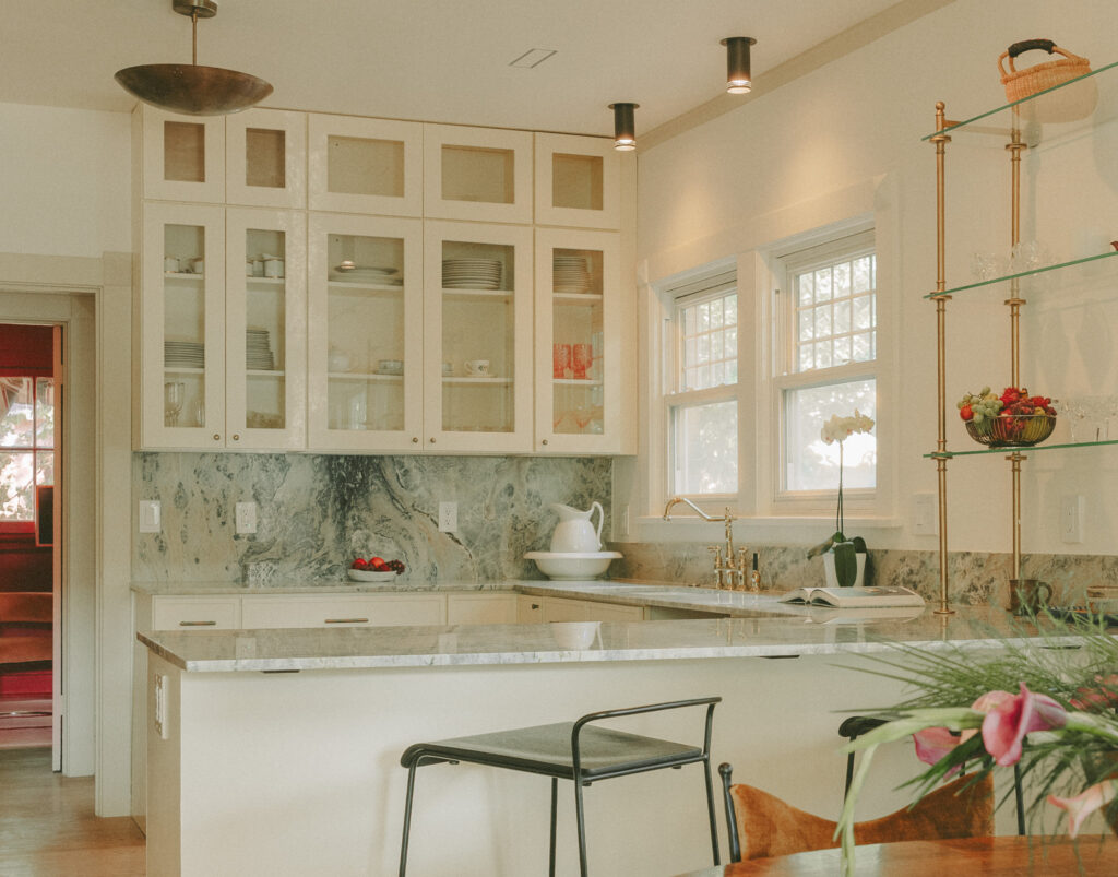 Ivory kitchen with glass-front cabinetry quartzite countertops and brass shelving by Tenlie Mourning interior designer. Madison street project